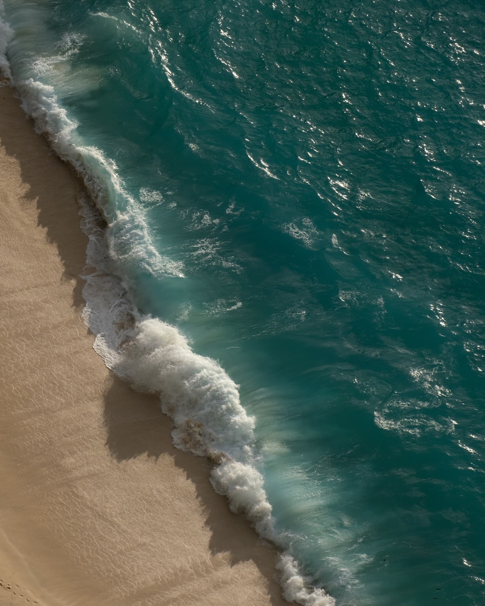 Aerial view of turquoise sea meeting golden sand